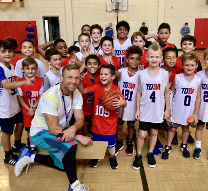 Coach Teddy kneeling with a full squad of TDBA campers in TDBA jerseys
