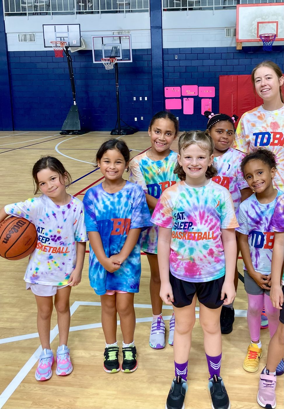 Girls at a TDBA camp lined up on the court in tie-dye TDBA shirts